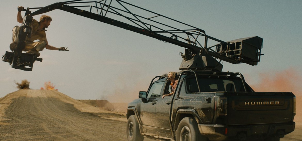 A truck with a jib crane drives through a desert.
