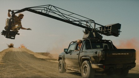 A truck with a jib crane drives through a desert.