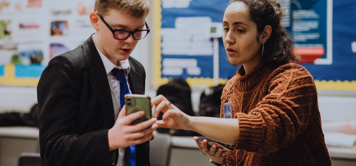 Teacher supporting student with mobile phone filmmaking