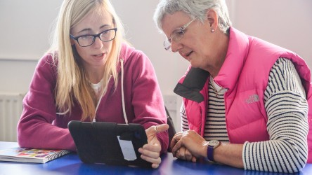 Two educators browsing on an ipad while chatting