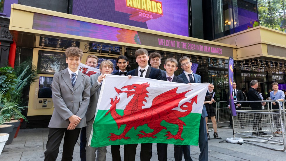 Filmmakers from Ysgol Bro Dinefwr pose with a Welsh flag.