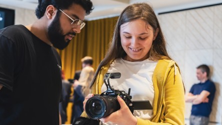 Young person using a camera with instructor helping