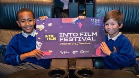 Two boys pose with our Into Film Festival poster.