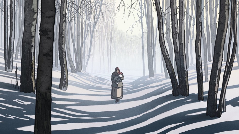 A woman walking through the snow in a forest holding a small bundle.