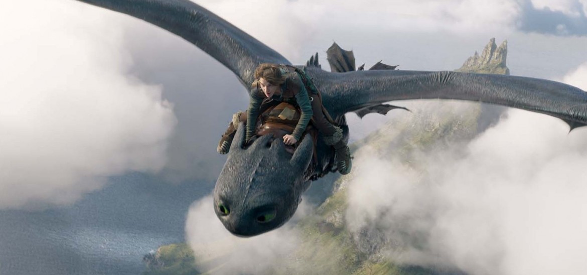 A grey dragon flying over an island and cloud, with a boy on top of it.