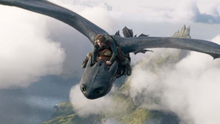 A grey dragon flying over an island and cloud, with a boy on top of it.