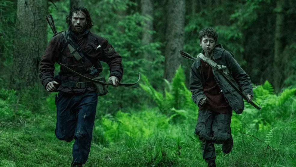 A man and a boy run through a forest