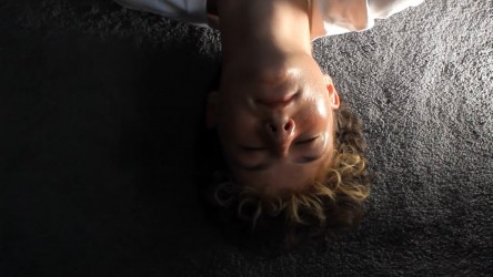 A young person lies with their eyes closed