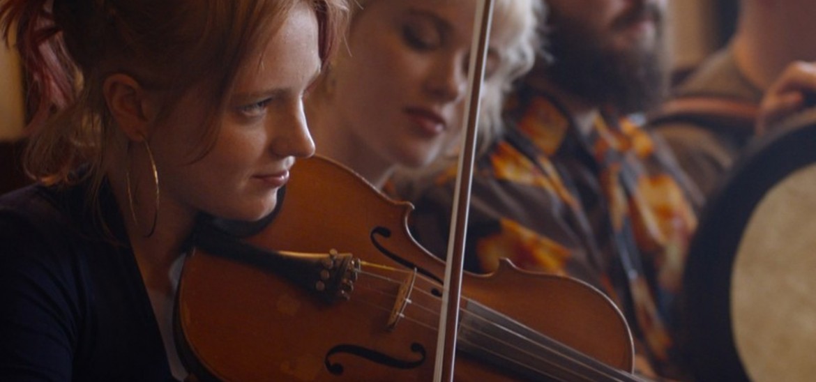 A young woman plays the violin within a musical group