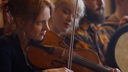A young woman plays the violin within a musical group
