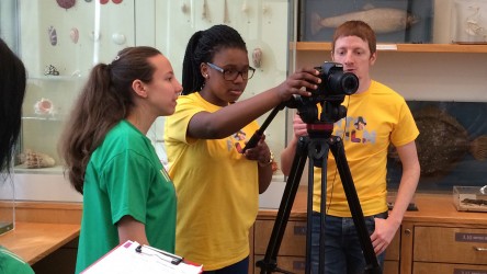 Two girls behind camera with one boy to side, in Into Film t-shirts. 