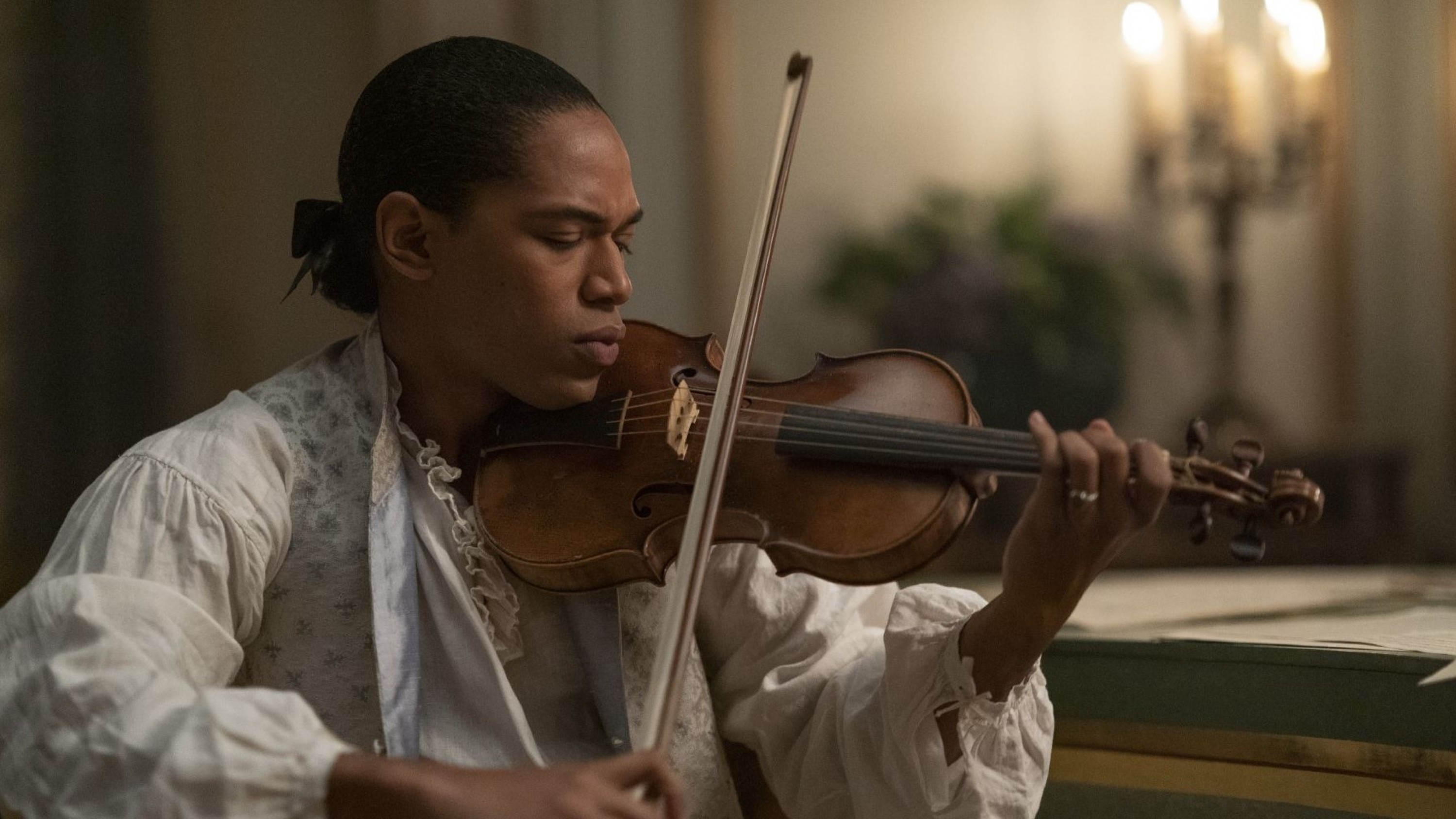 A Black man in 18th century clothing plays violin