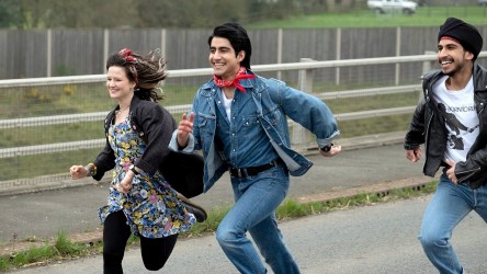Three young people run happily through a street.