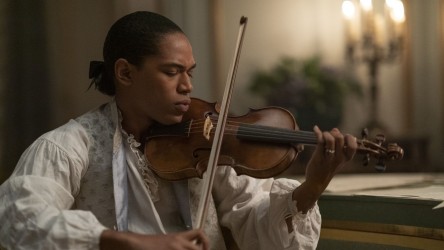 A Black man in 18th century clothing plays violin